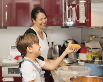 Eine Frau und ein Kind stehen in einer Küche und kochen fröhlich
